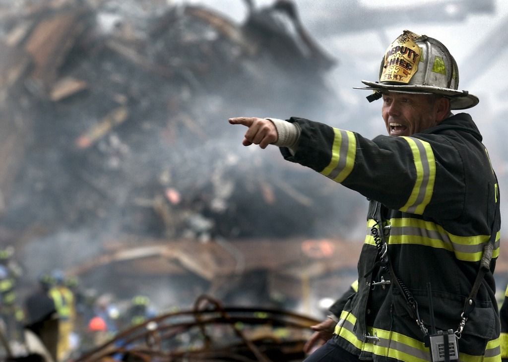 Firefighter pointing while standing in front of a collapsed structure